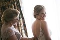 Mother of the bride making adjustments to daughter's wedding dress