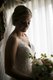 Bride posing with bouquet near window with dramatic lighting
