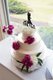 White tiered wedding cake with pearl icing and magenta floral details