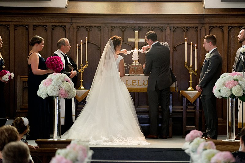 Bride and groom lighting candle on altar during wedding ceremony