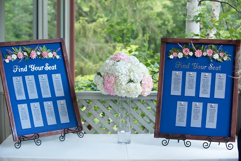 Wedding seating chart featuring small table lists affixed to wooden frames with floral details