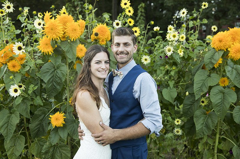 Photo of bride and groom in field of sunflowers