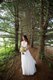 Bride posing with bouquet of flowers in copse of evergreen trees