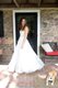 Bride in wedding dress posing in front of fieldstone wall with dog