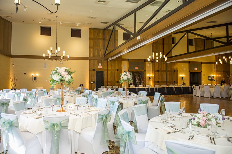 Wedding reception hall with white table linens and sea green accents