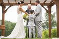 Bride and groom exchanging vows at outdoor wedding ceremony with pergola