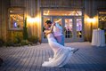 Groom dipping bride, sharing kiss in evening on stone patio outside of venue