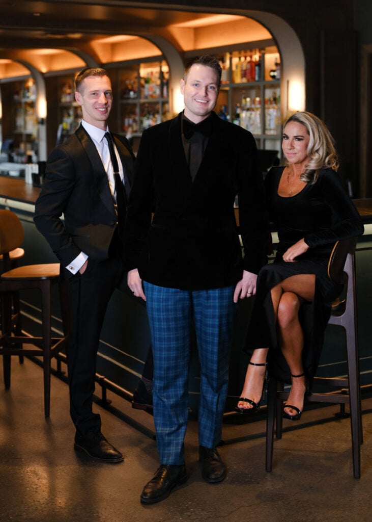 Garett Vassel, center, with two colleagues sitting at a bar