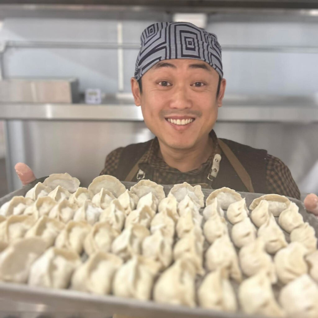 The chef of Angry Dumpling holding a tray of dumplings, one of this month's picks.