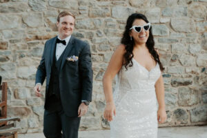 Photo of bride and groom at their wedding reception, the bride wearing a pair of novelty heart-shaped sunglasses.